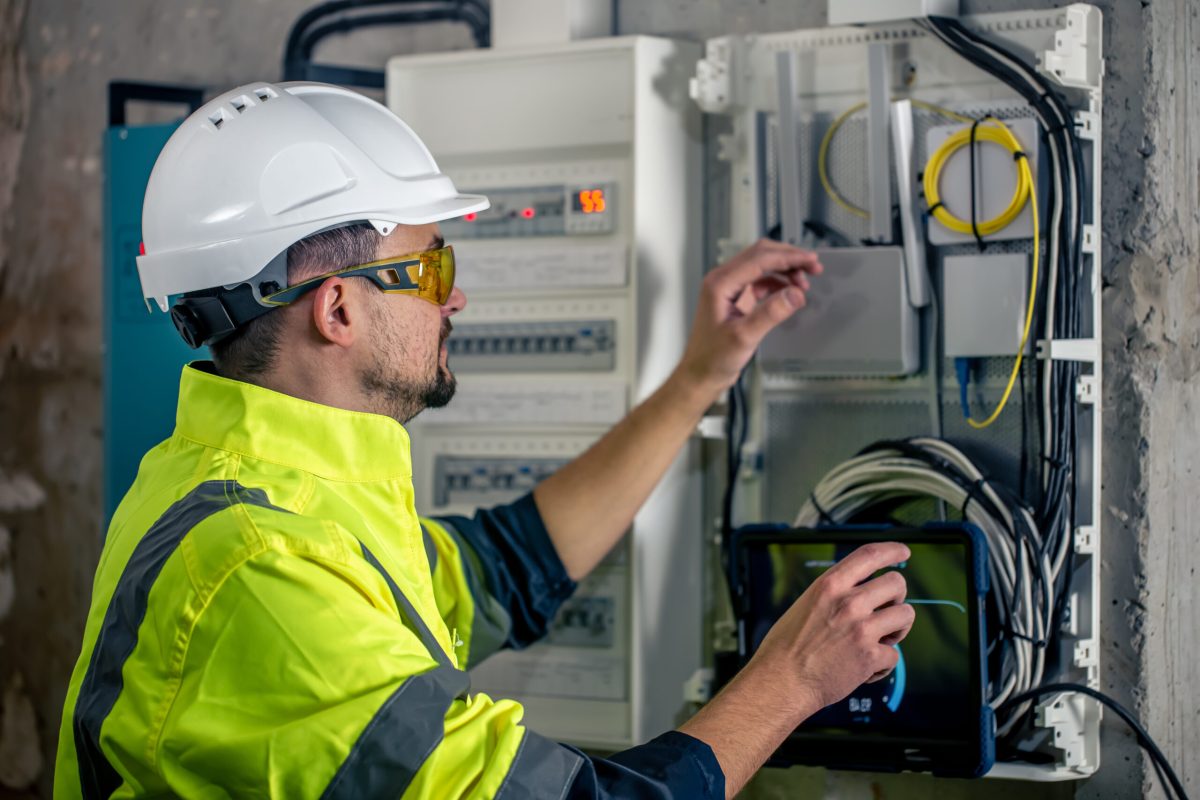 Man, an electrical technician working in a switchboard with fuses. Installation and connection of electrical equipment.